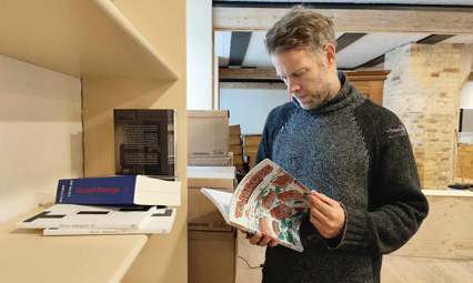 Claus Nivaa står med Dan Turèlls "Vangede billeder", Café Ordgeist, Aalborg, før åbningen.