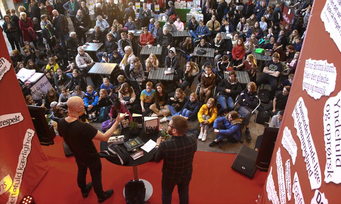 Kenneth Bøgh Andersen i samtale med Jacob Skou Bæk i Kedelhallen i Nordkraft. Foran scenen sidder og står en masse unge mennesker